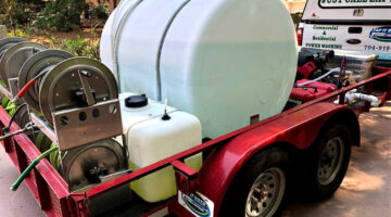 A power washing trailer being used to power wash a home.